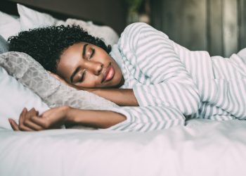 close up of a pretty black woman with curly hair sleeping in bed closed eyes