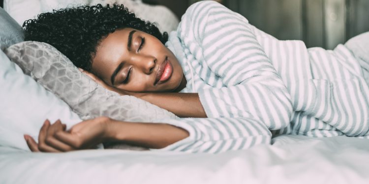 close up of a pretty black woman with curly hair sleeping in bed closed eyes