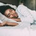 close up of a pretty black woman with curly hair sleeping in bed closed eyes